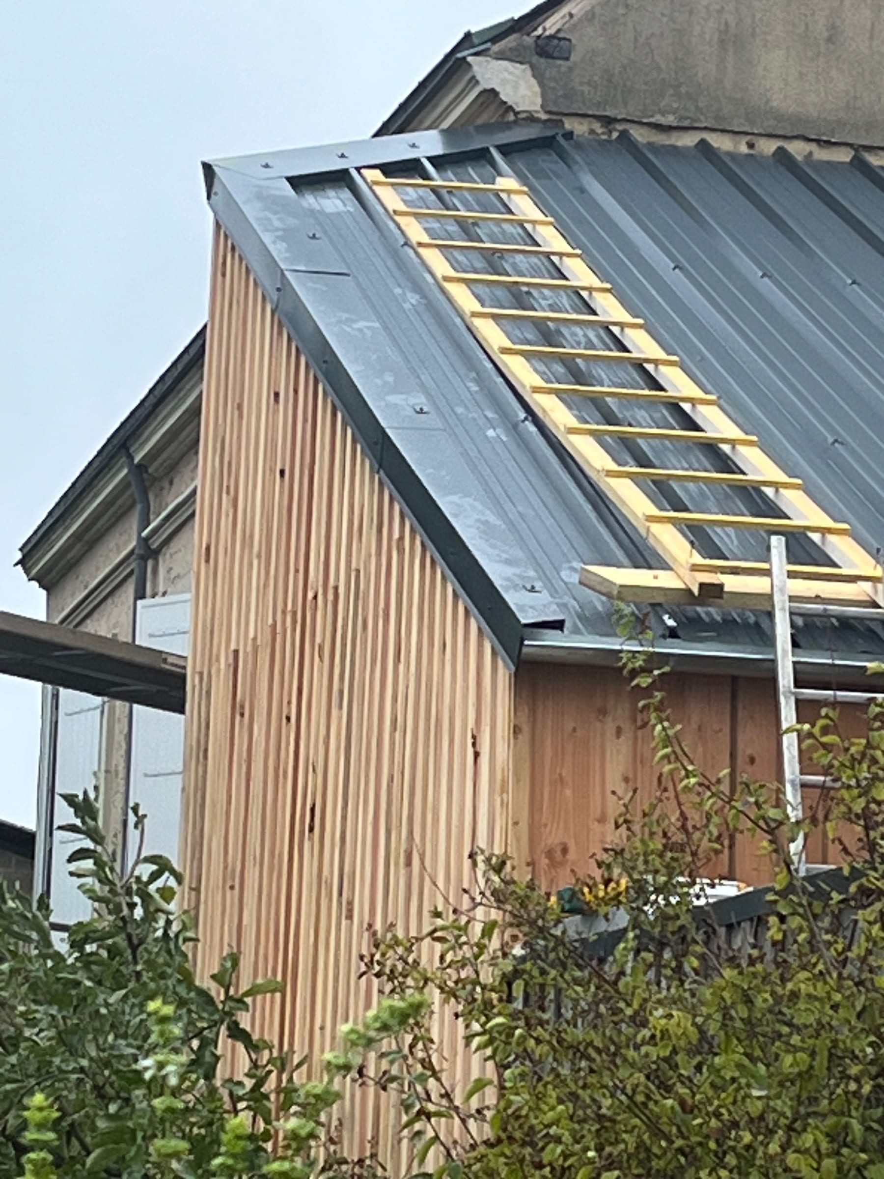 Couverture en cours de pose sur une extension bardée de bois