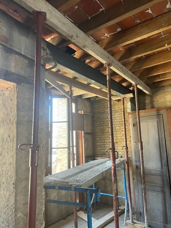 Pièce en cours de rénovation avec poutres et étais de chantier