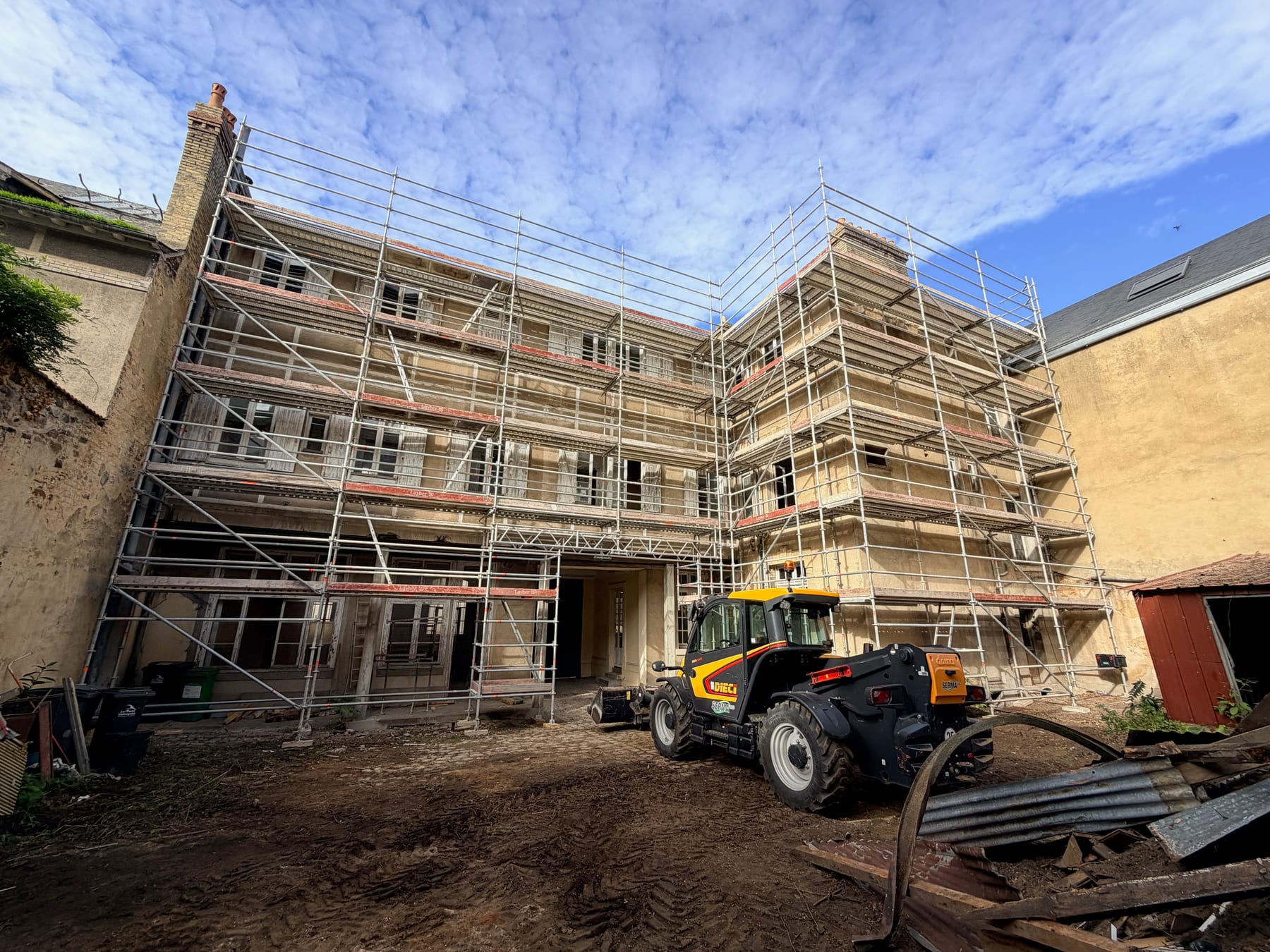 Façade d’immeuble en travaux avec échafaudage dans une cour au Mans