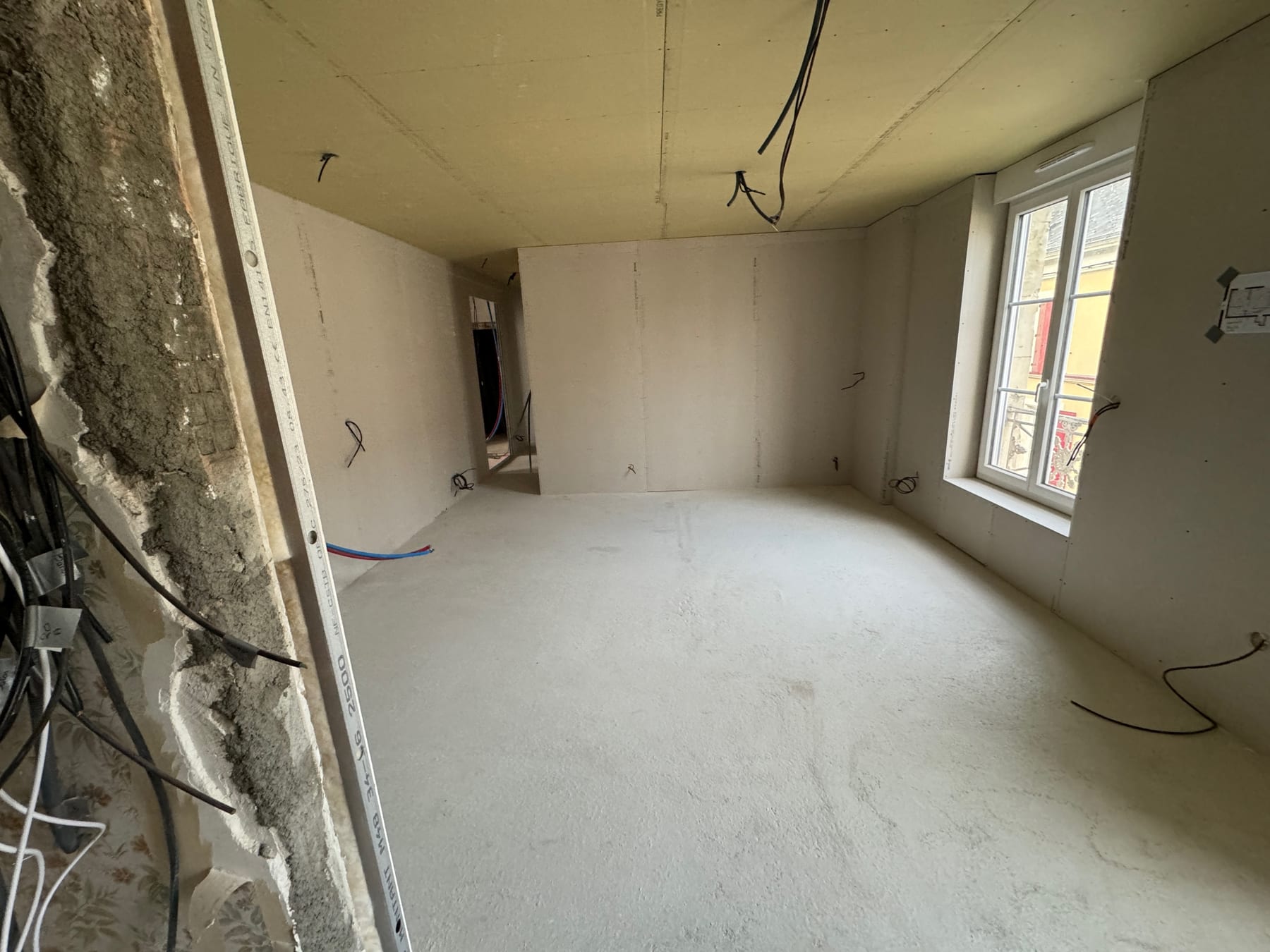 Pièce en cours de rénovation avec cloisons, plafond et réseaux apparents